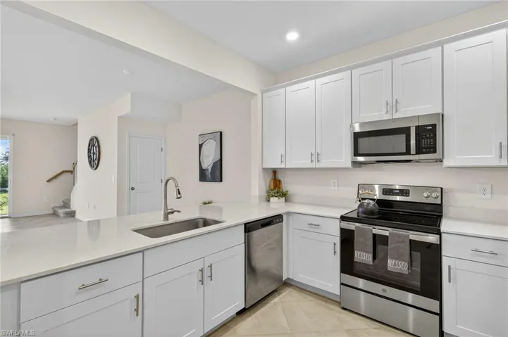 Kitchen featuring appliances with stainless steel finishes, light countertops, white cabinetry, light tile patterned floors, and recessed lighting