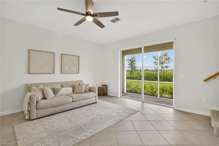 Tiled living room featuring ceiling fan and baseboards