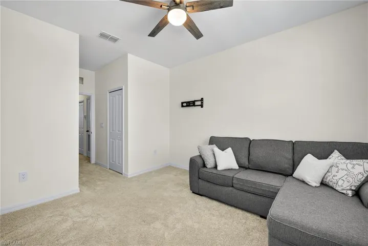 Carpeted living area featuring a ceiling fan and baseboards