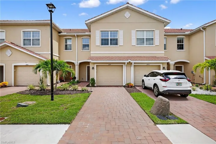 Townhome / multi-family property featuring driveway, a garage, stucco siding, and a tile roof