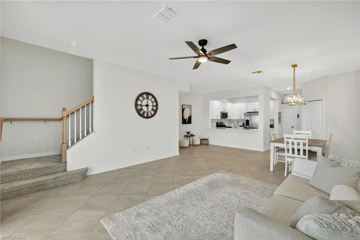 Living area featuring stairway, light tile patterned floors, ceiling fan, and a chandelier