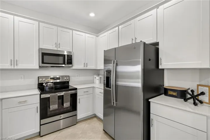 Kitchen featuring appliances with stainless steel finishes, light countertops, white cabinetry, light tile patterned flooring, and recessed lighting