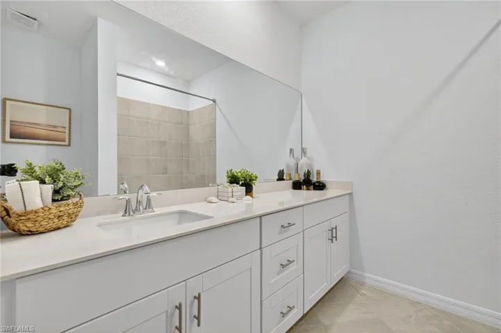 Bathroom featuring vanity, a tile shower, and tile patterned flooring
