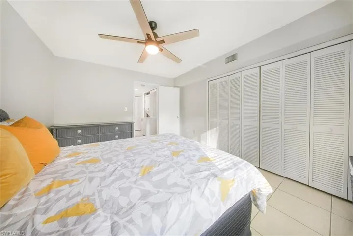 Bedroom featuring light tile patterned floors, ceiling fan, and a closet
