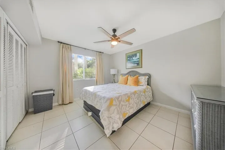 Bedroom with a ceiling fan, light tile patterned floors, and a closet