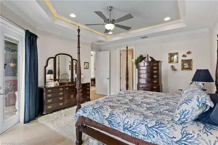 Bedroom featuring crown molding, a tray ceiling, ceiling fan, and light hardwood / wood-style flooring