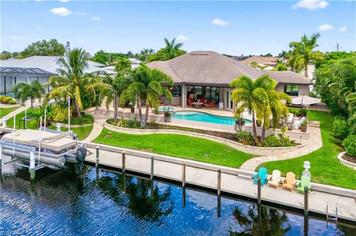 Back of property featuring a lawn, a water view, and a patio area