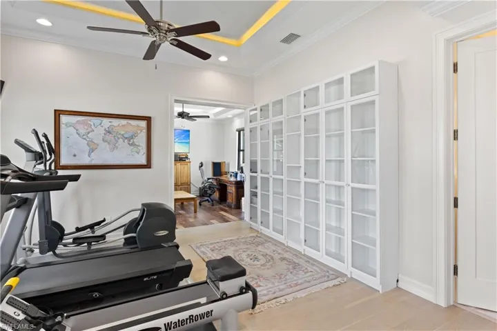 Exercise area featuring light hardwood / wood-style floors, ceiling fan, and crown molding