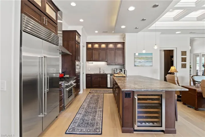 Kitchen featuring dark stone counters, high end appliances, wine cooler, and light hardwood / wood-style flooring