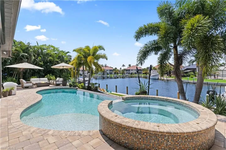 View of pool with a patio, a water view, and an in ground hot tub