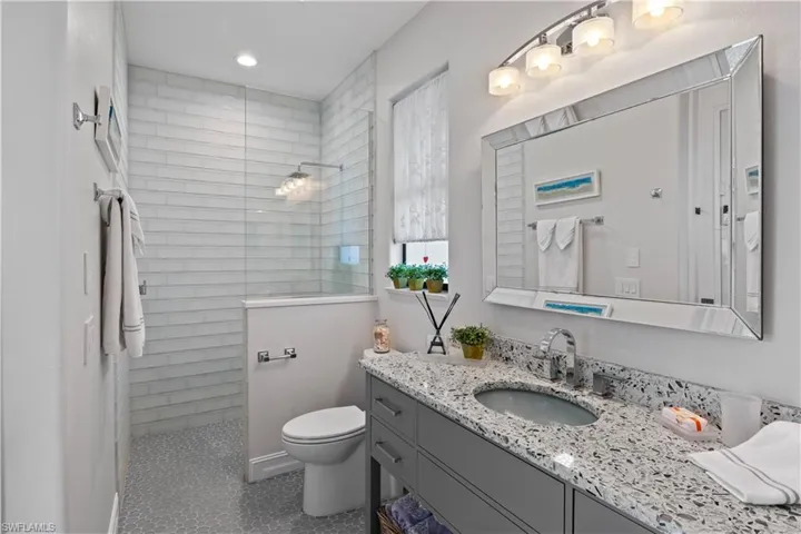 Bathroom featuring a tile shower, vanity, toilet, and tile patterned floors