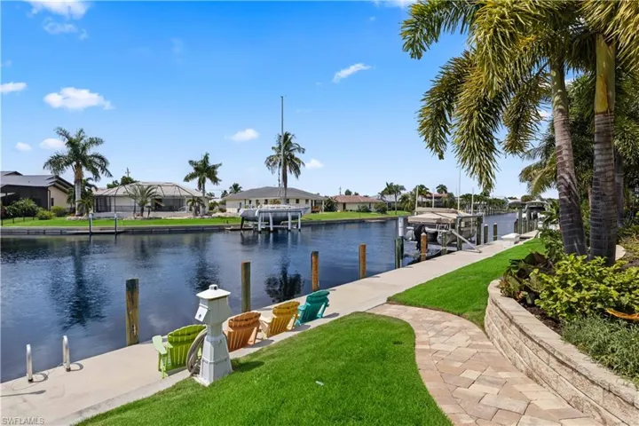 View of dock with a yard, glass enclosure, and a water view