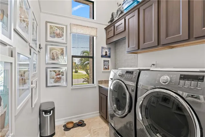 Clothes washing area with separate washer and dryer, light tile patterned floors, and cabinets