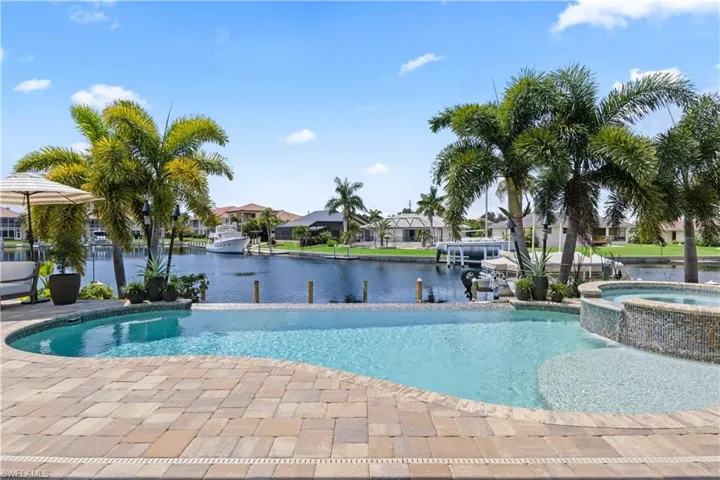 View of pool with a patio, a water view, and an in ground hot tub