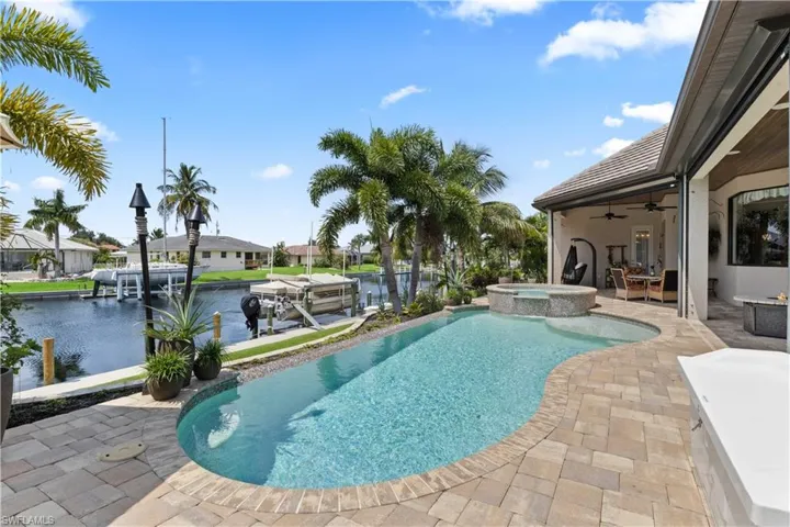 View of swimming pool with ceiling fan, a water view, an in ground hot tub, and a patio area