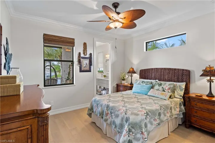 Bedroom with ornamental molding, ensuite bath, light hardwood / wood-style flooring, and ceiling fan