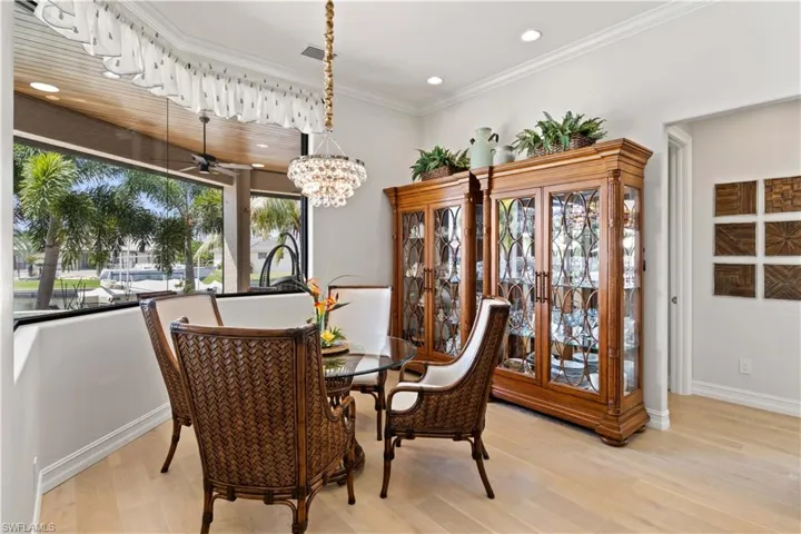 Dining area featuring light wood-type flooring, ceiling fan with notable chandelier, and ornamental molding