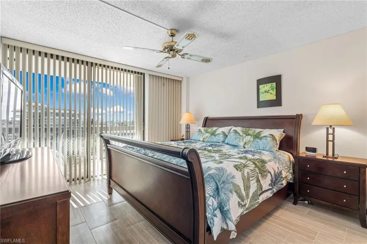 Bedroom with ceiling fan, a textured ceiling, and access to exterior