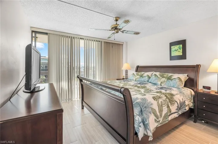 Bedroom with ceiling fan, a textured ceiling, light wood-type flooring, and expansive windows
