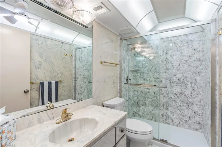 Bathroom with vanity, a shower with shower door, and toilet