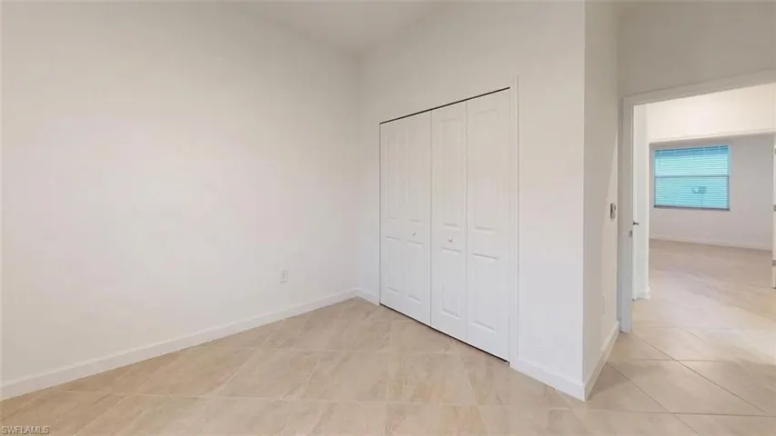 Neutral tone wall paint, tile flooring, and a bi-fold closet door