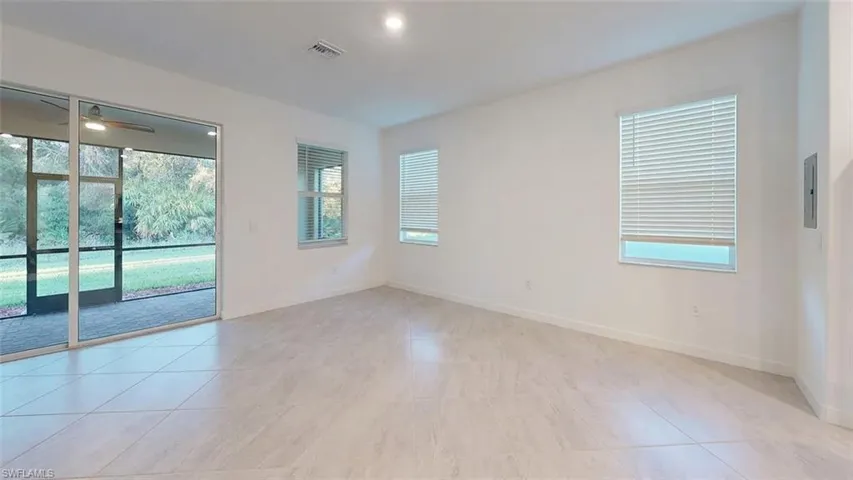 Recessed lighting, large format tile flooring, multiple windows with blinds, a sliding glass door, and a screened lanai with a ceiling fan