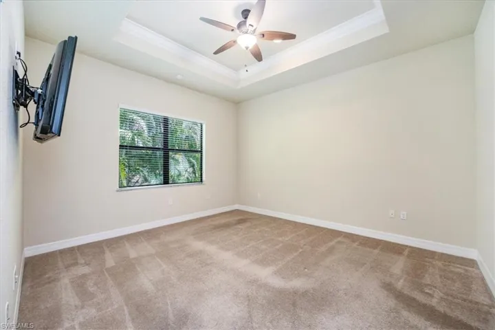 Carpeted spare room with baseboards, ceiling fan, ornamental molding, and a raised ceiling