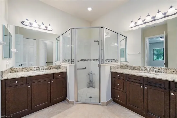 Full bathroom featuring two vanities, a sink, and a stall shower