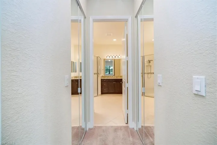 Corridor with light carpet, a textured wall, and light tile patterned floors