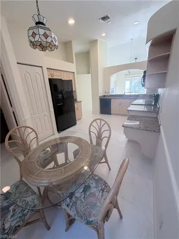 Dining space with a high ceiling, recessed lighting, arched walkways, and light marble finish flooring