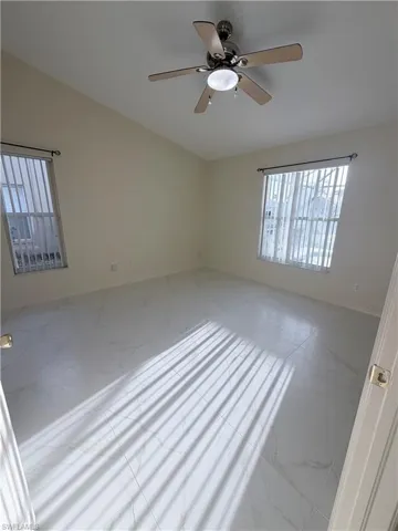 Unfurnished room with ceiling fan and light marble finish floors