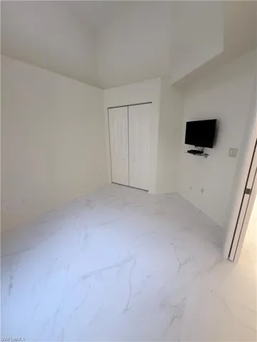 Unfurnished bedroom with a closet and light marble finish floors