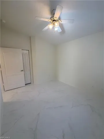 Spare room with ceiling fan and light marble finish flooring