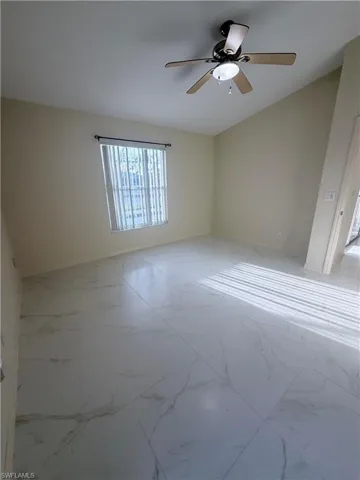 Spare room with light marble finish floors and a ceiling fan