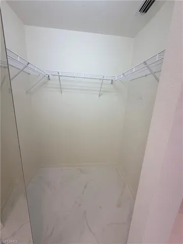 Walk in closet featuring light marble finish floors