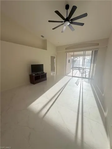 Unfurnished room featuring arched walkways, light marble finish flooring, ceiling fan, and vaulted ceiling