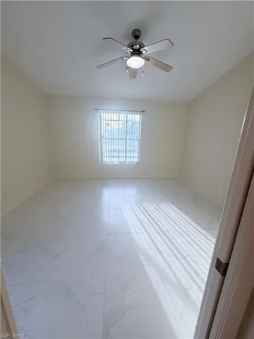 Spare room with light marble finish floors and ceiling fan
