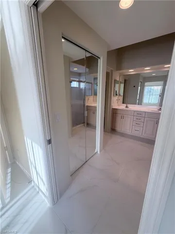 Full bath with double vanity, a stall shower, and plenty of natural light