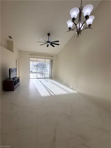 Spare room featuring hanging lights, ceiling fan, lofted ceiling, and light marble finish floors