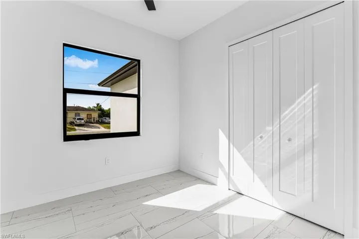 Unfurnished bedroom featuring light marble finish flooring and a ceiling fan