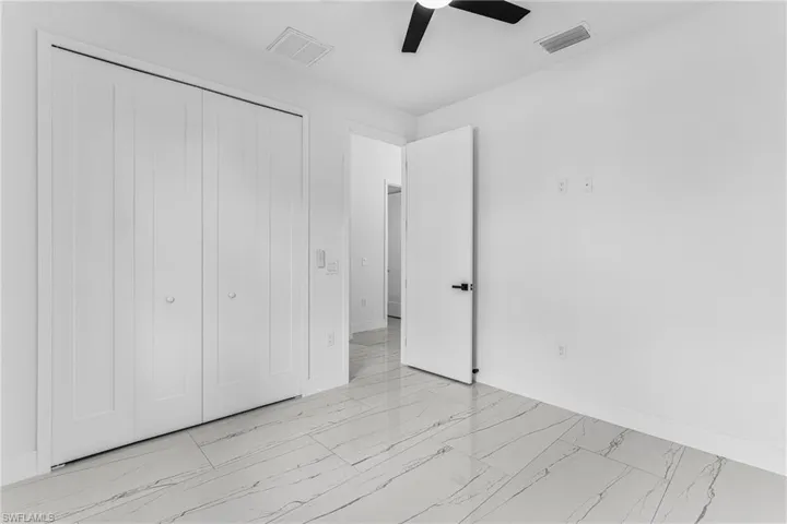 Unfurnished bedroom with light marble finish floors, a closet, and a ceiling fan