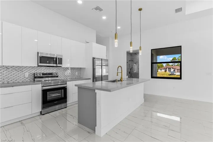 Kitchen with stainless steel appliances, modern cabinets, and white cabinetry