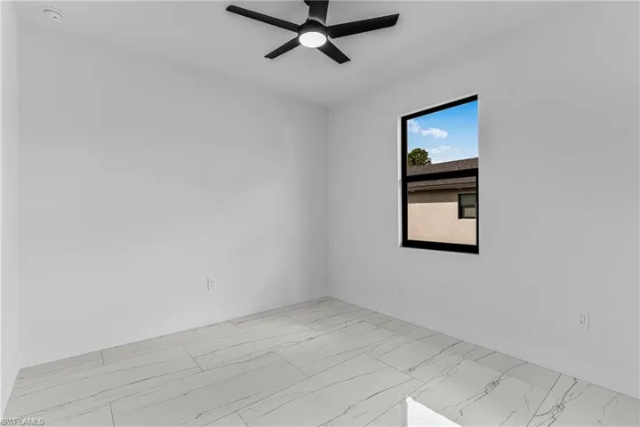 Unfurnished room featuring light marble finish floors and ceiling fan
