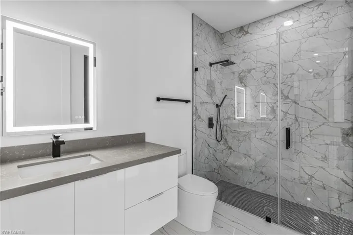 Full bathroom featuring a marble finish shower and vanity