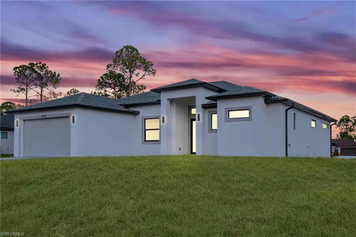 Prairie-style house with stucco siding, an attached garage, and a lawn