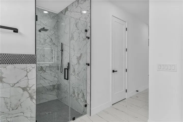 Bathroom with a marble finish shower and baseboards