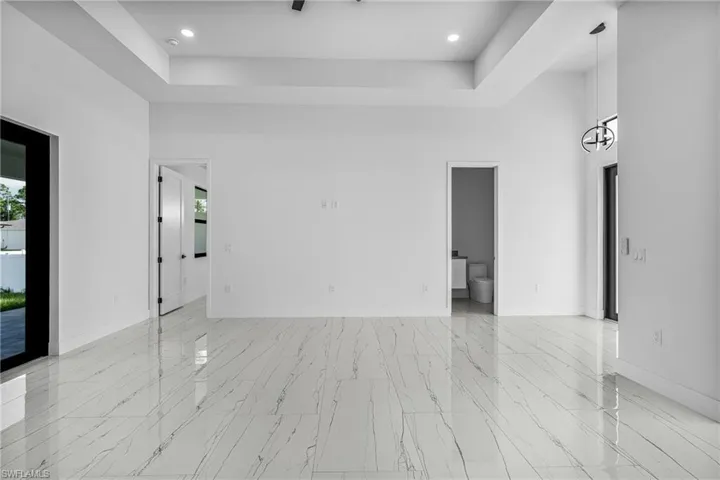 Spare room with a high ceiling, recessed lighting, and light marble finish flooring