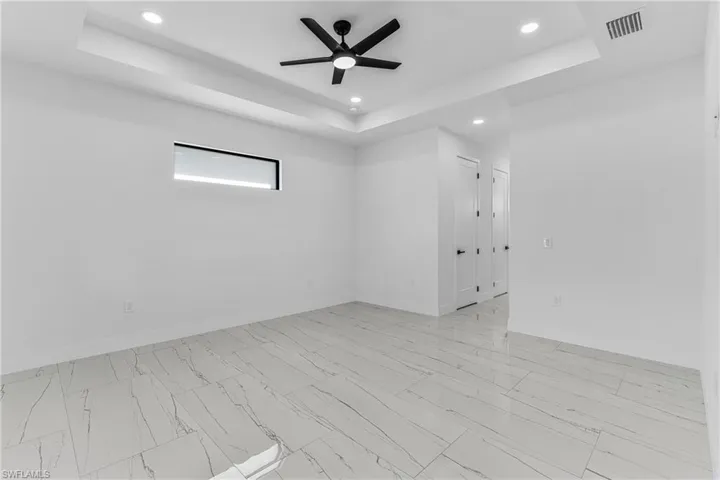 Spare room with a raised ceiling, recessed lighting, and a ceiling fan