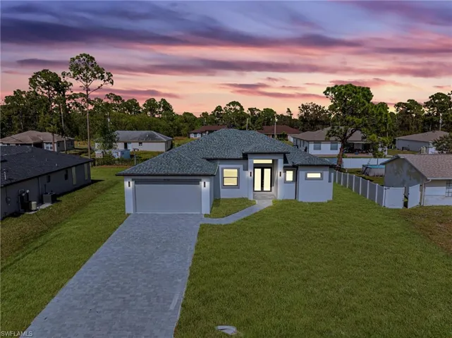 View of front of property with decorative driveway, stucco siding, a garage, and a residential view