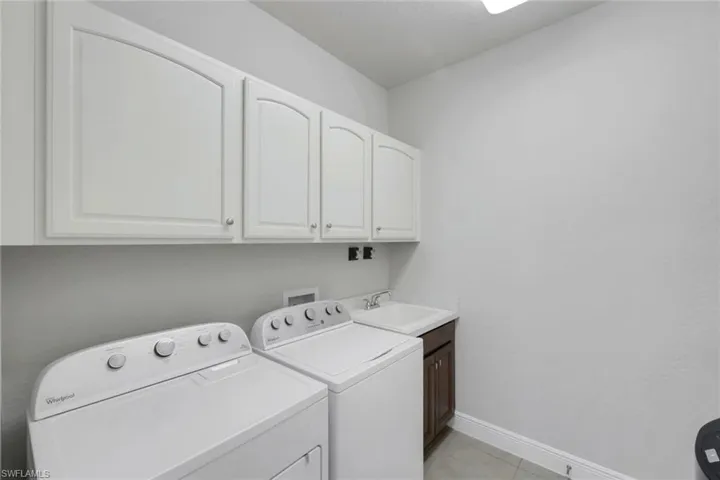 Laundry room with independent washer and dryer, cabinet space, and light tile patterned floors
